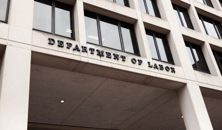 The exterior view of the building showcases a Department of Labor sign above the entrance, with large windows and concrete columns, indicating its role in managing diverse needs, from IT staffing to engineering staffing for independent contractors.