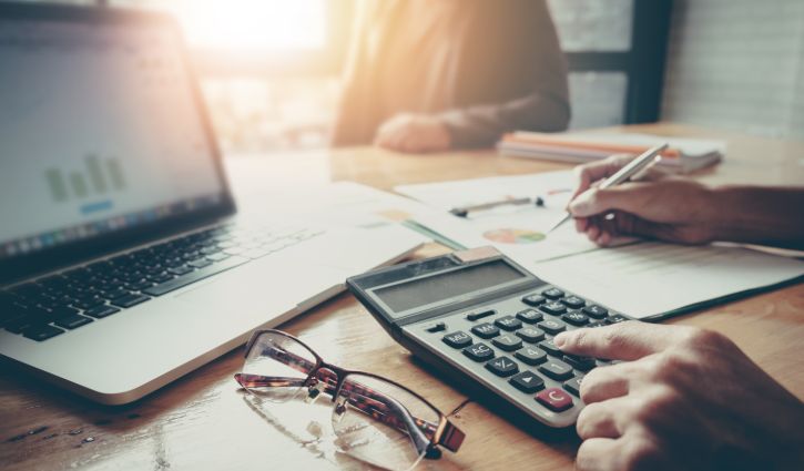 Close up Businessman and partner using calculator and laptop for calaulating finance, tax, accounting, statistics and analytic research concept