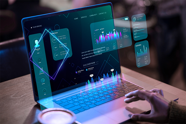 A person uses a laptop displaying futuristic, holographic market data charts and interface elements above the keyboard, with a cup of coffee nearby on the desk.